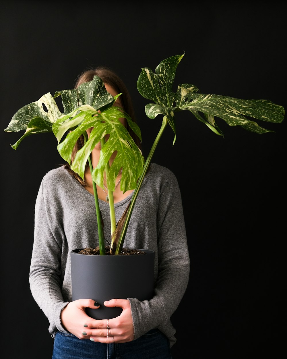 Una mujer sosteniendo una planta en maceta frente a su cara