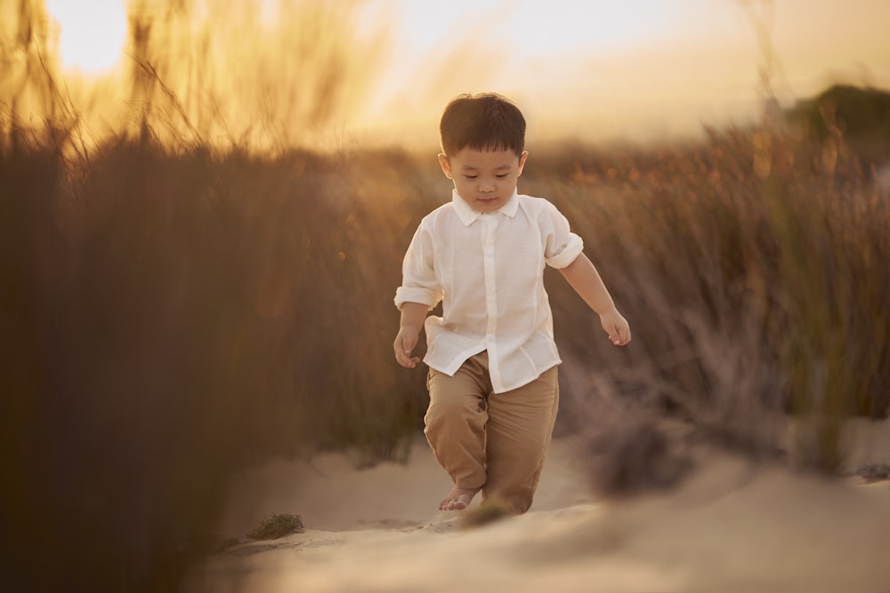 a young boy is walking in the sand