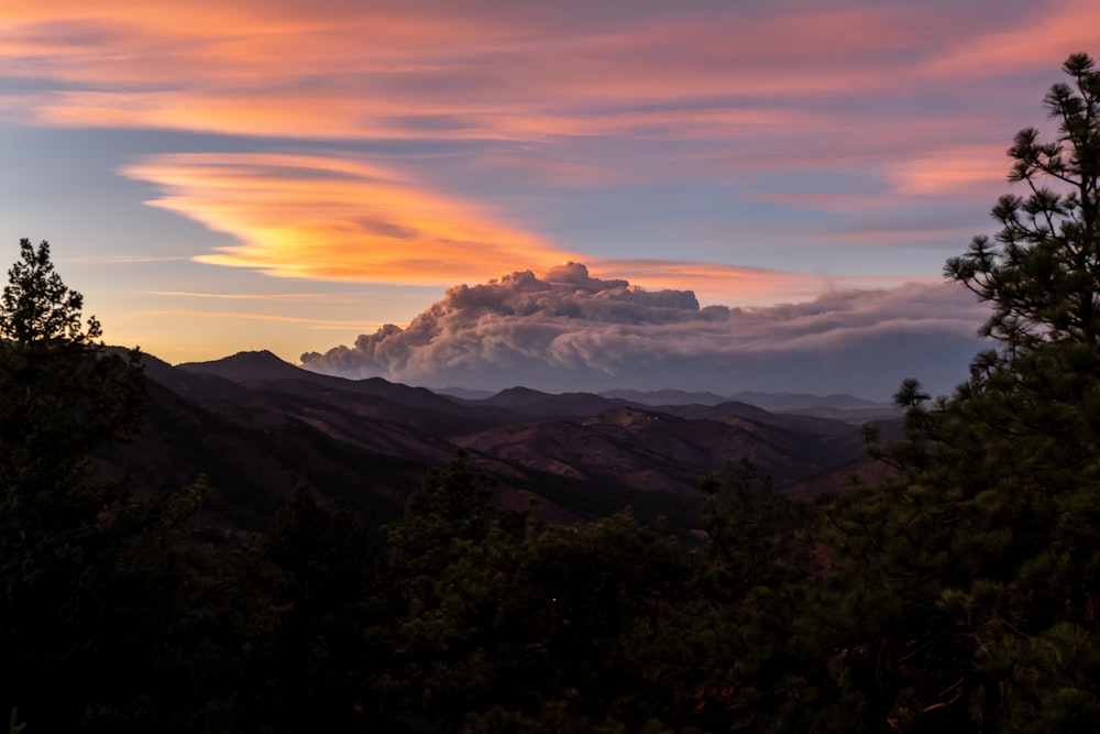 a sunset view of a mountain range with clouds in the sky