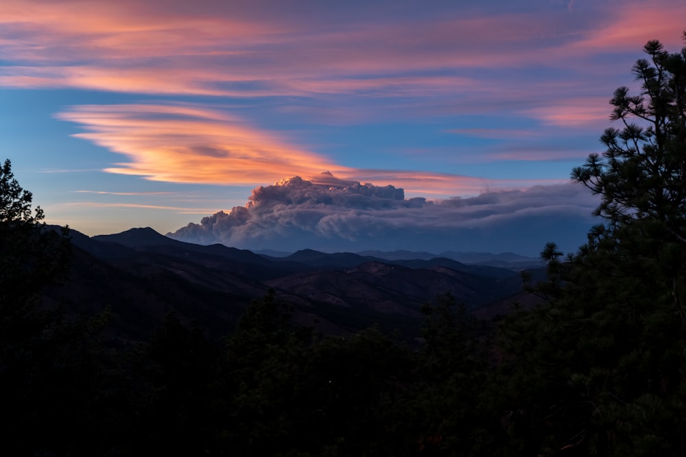 a sunset view of a mountain range with clouds in the sky