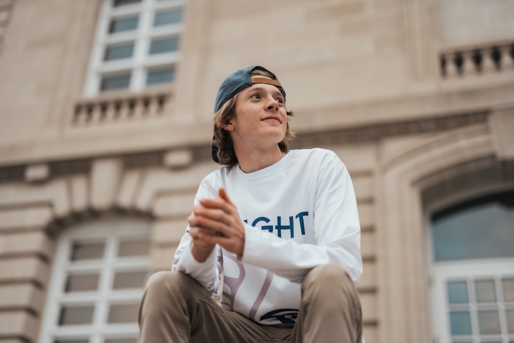 a man sitting on a ledge in front of a building