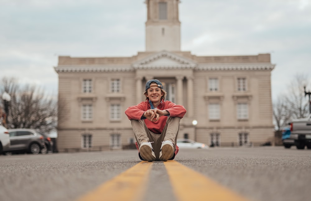 a person sitting on the ground in front of a building