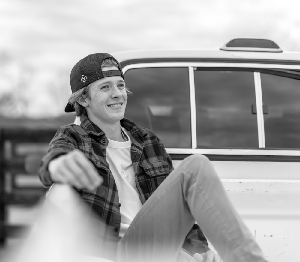 a young man sitting in front of a white van