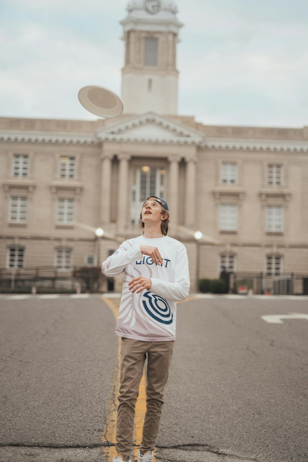 a man standing in front of a large building throwing a frisbee