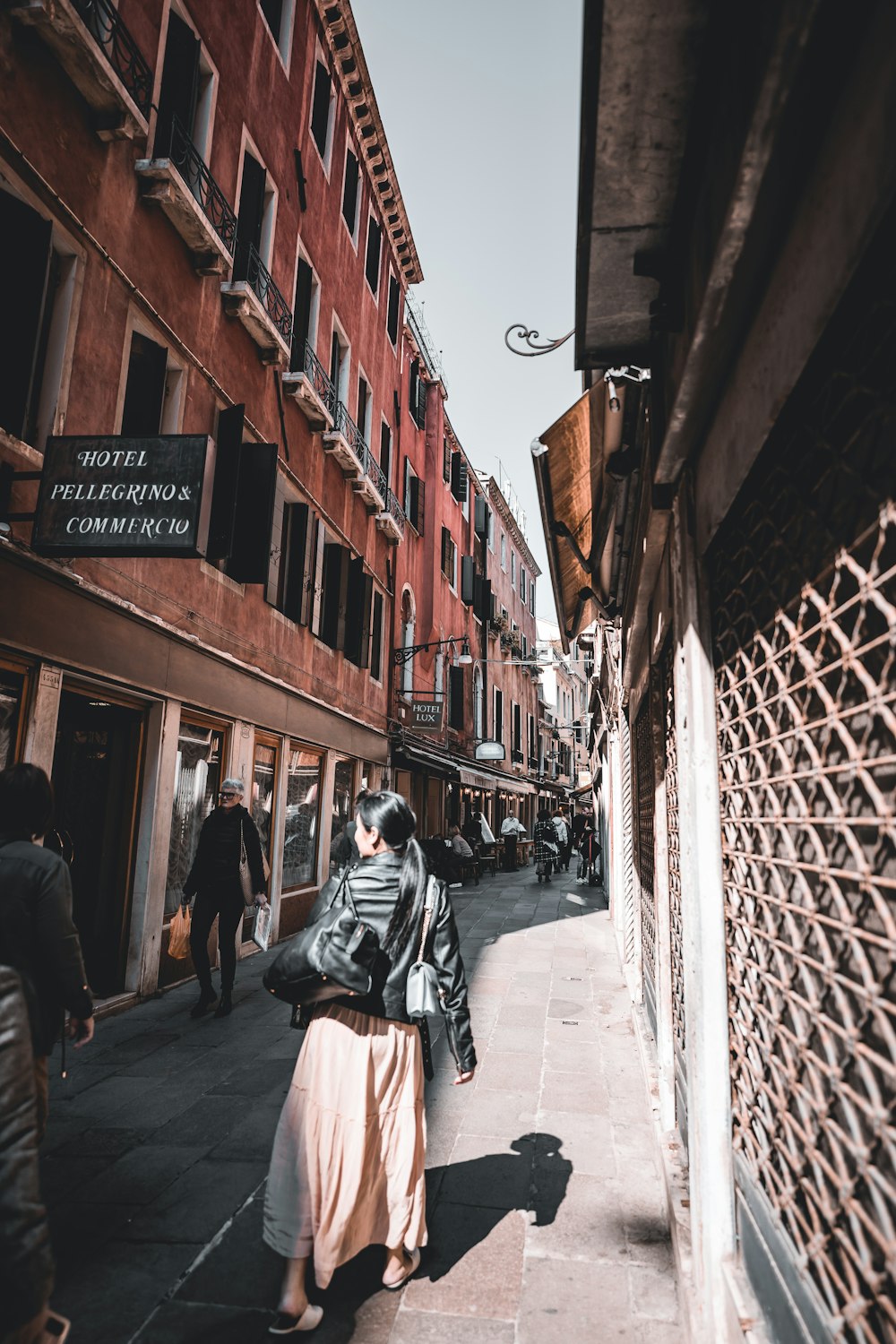 a woman walking down a street next to tall buildings