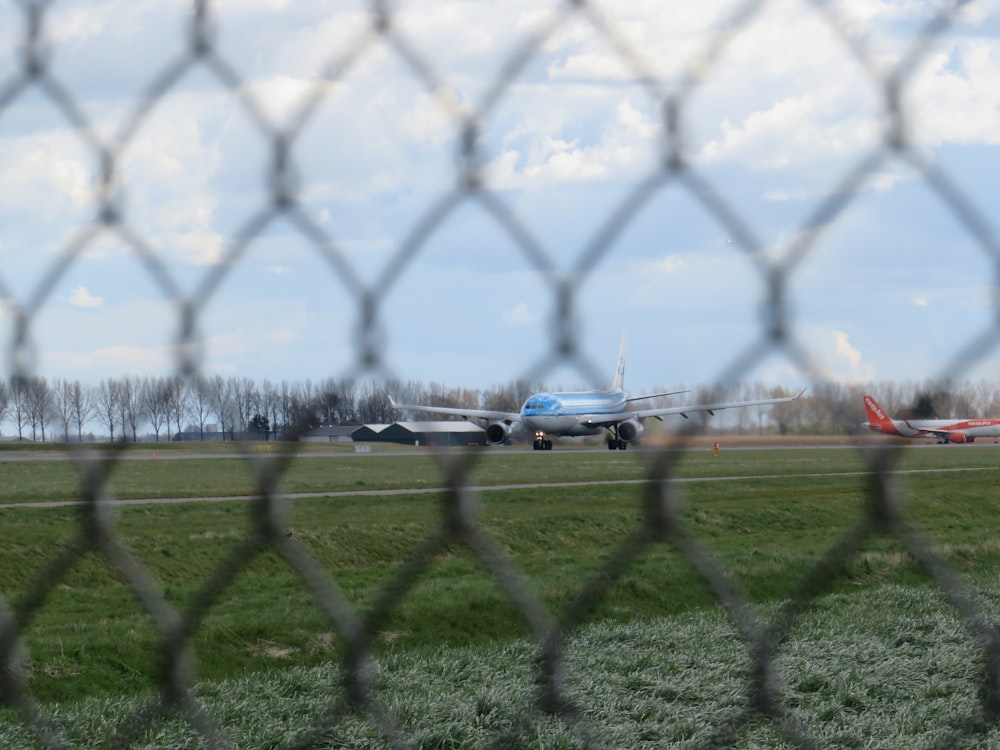 a plane on a runway behind a fence