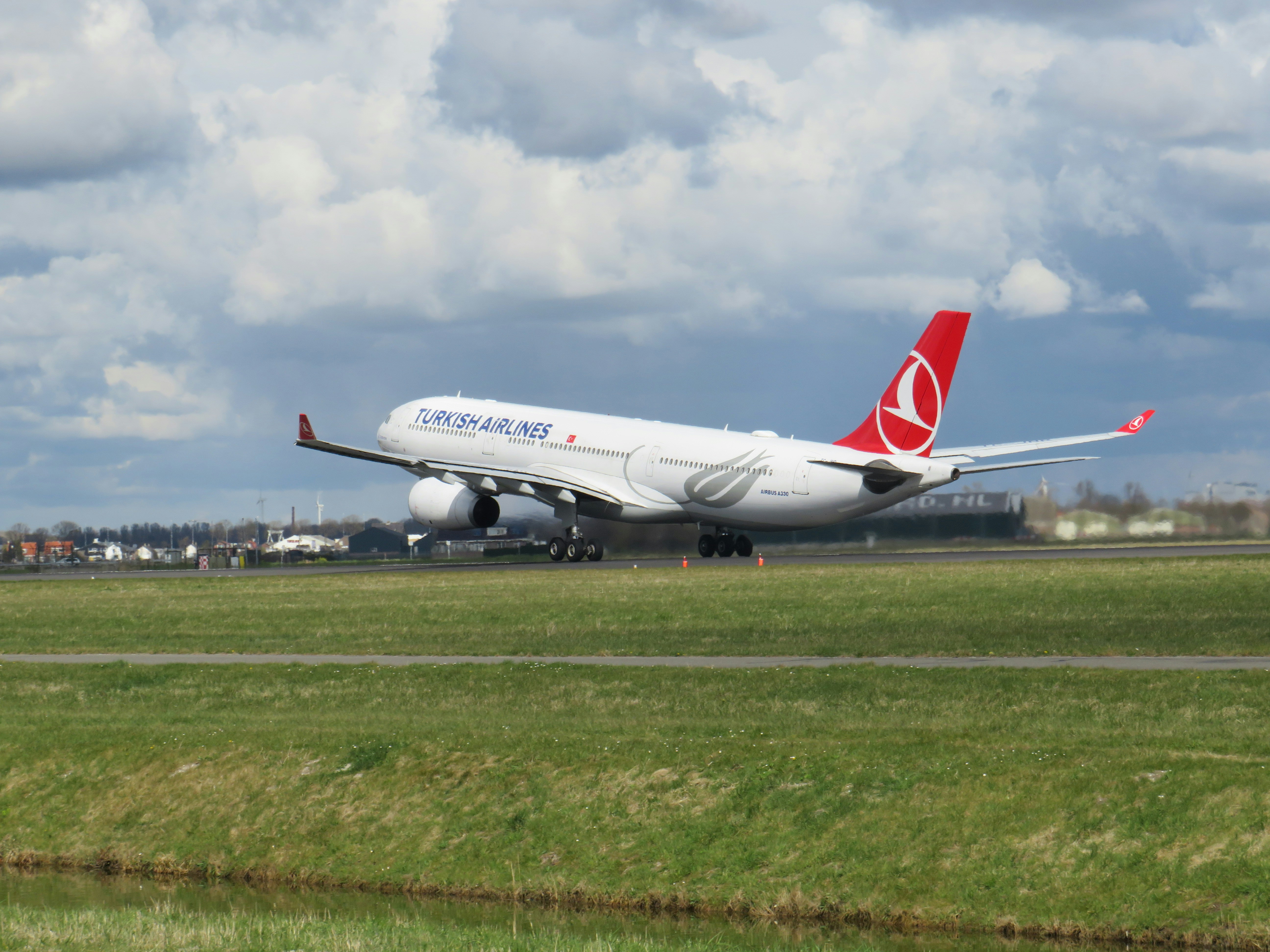 a large jetliner sitting on top of an airport runway, An Turkish Airlines plane during takeoff on Schiphol Airport