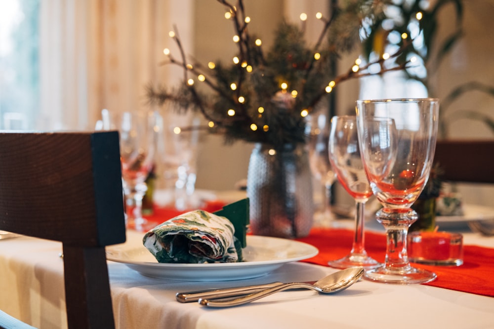 a table set for a holiday dinner with wine glasses and silverware