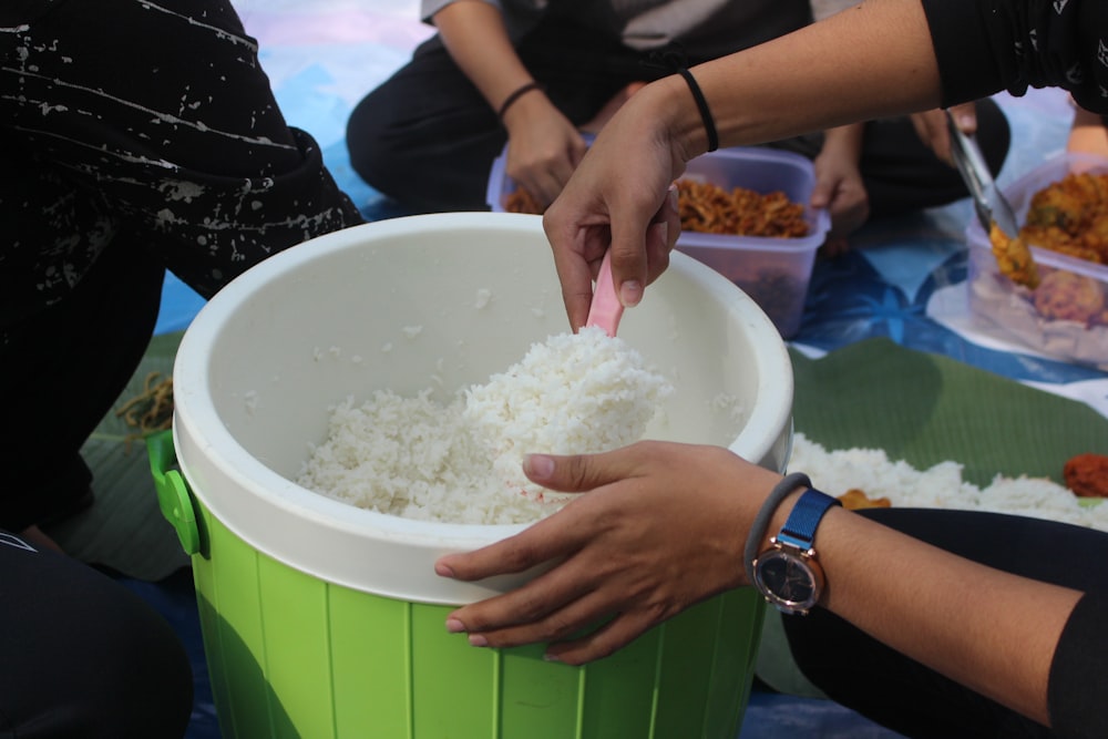 a group of people sitting around a bucket of rice