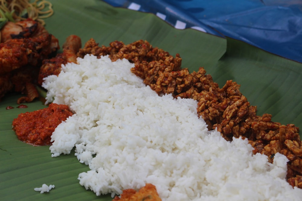 a close up of rice and meat on a banana leaf