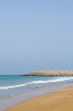 a person walking on the beach with a surfboard