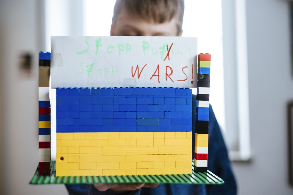 a young boy holding a lego model of a building