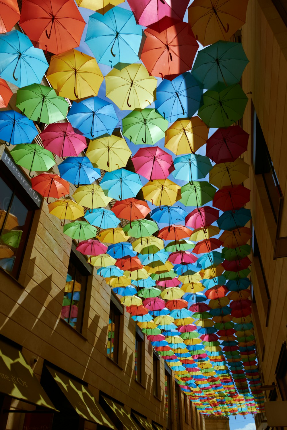 a room filled with lots of colorful umbrellas hanging from the ceiling