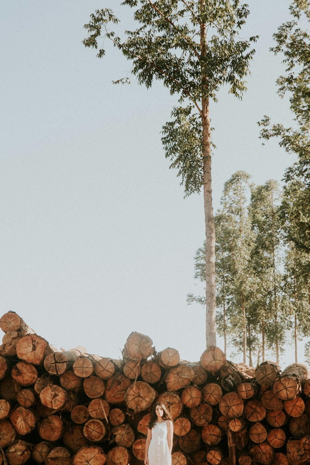 a woman standing in front of a pile of logs