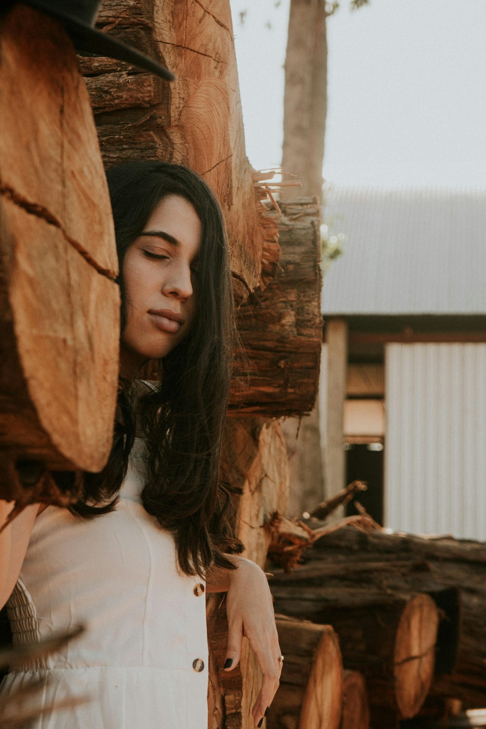 uma mulher de pé ao lado de uma pilha de troncos