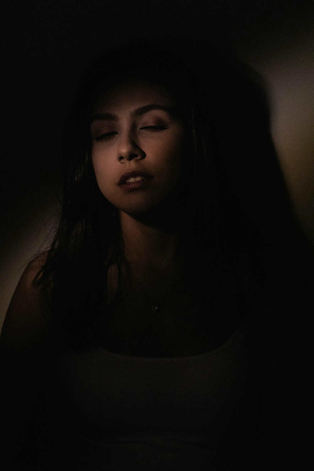 a woman with her eyes closed in the dark