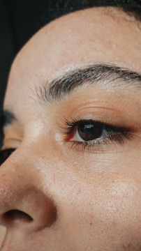 Close-up of perfectly micropigmented eyebrows on a smiling woman.