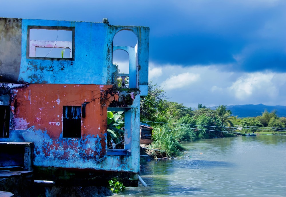 a blue and red building sitting on the side of a river