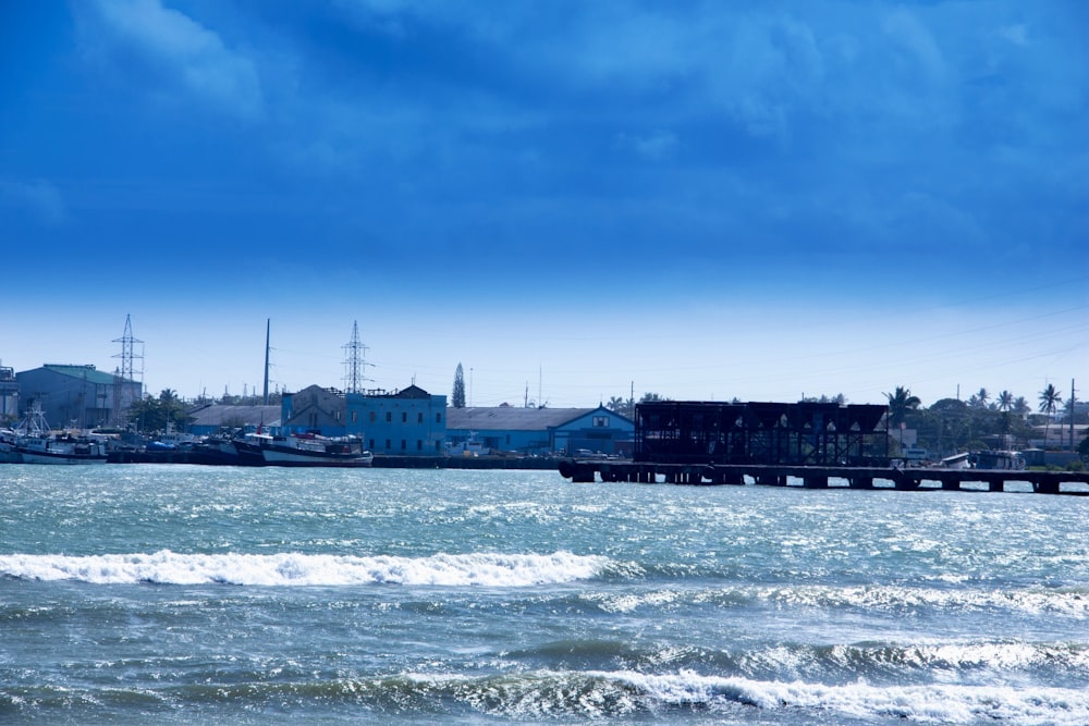 a body of water with a pier and buildings in the background