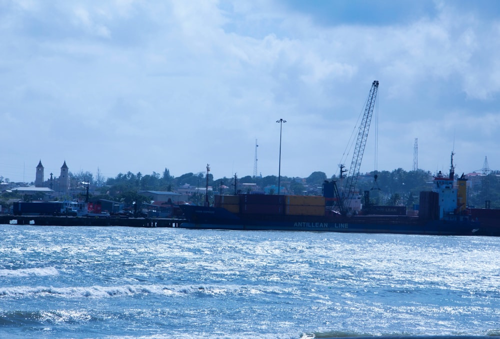 a large cargo ship in the water with a city in the background