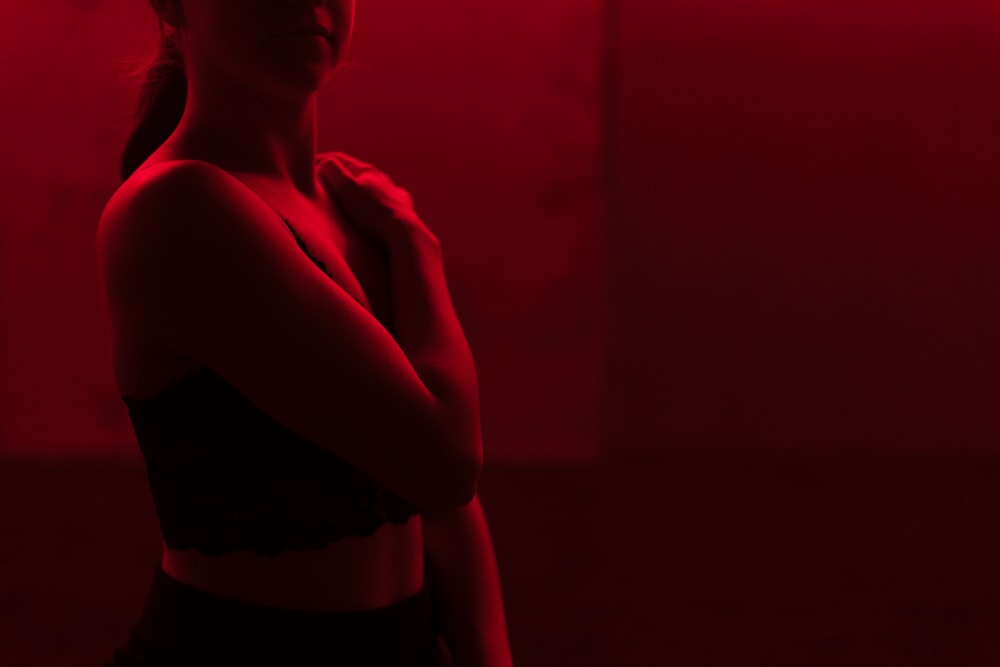 a woman standing in a dark room with her arms crossed