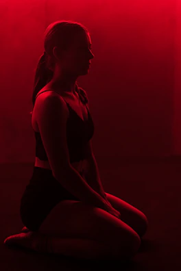 A dark, intense silhouette of a meditating warrior surrounded by deep red and black shadows.