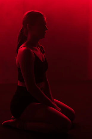 A silhouette of a meditating warrior bathed in deep red light, embodying spiritual depth and discipline.