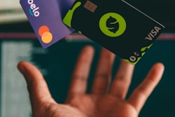 a hand holding a credit card in front of a computer