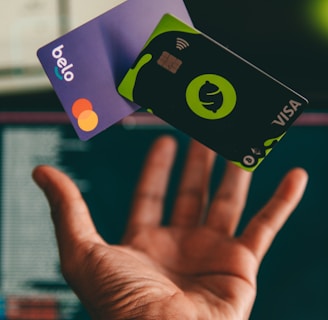 a hand holding a credit card in front of a computer