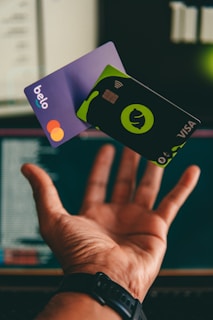 a hand holding a credit card in front of a computer