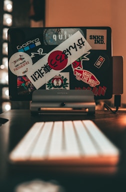 A close-up of a hand selecting a sticker from a modern laptop setup.