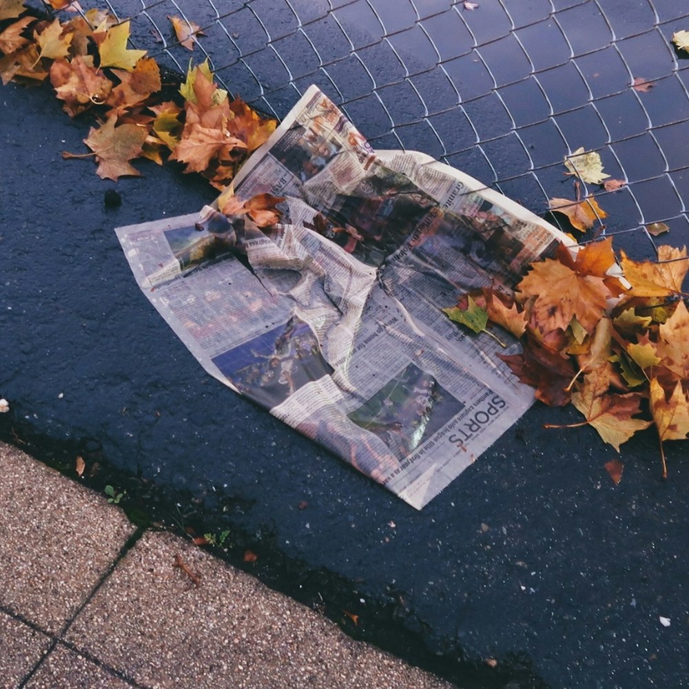 a newspaper laying on the ground next to a fence