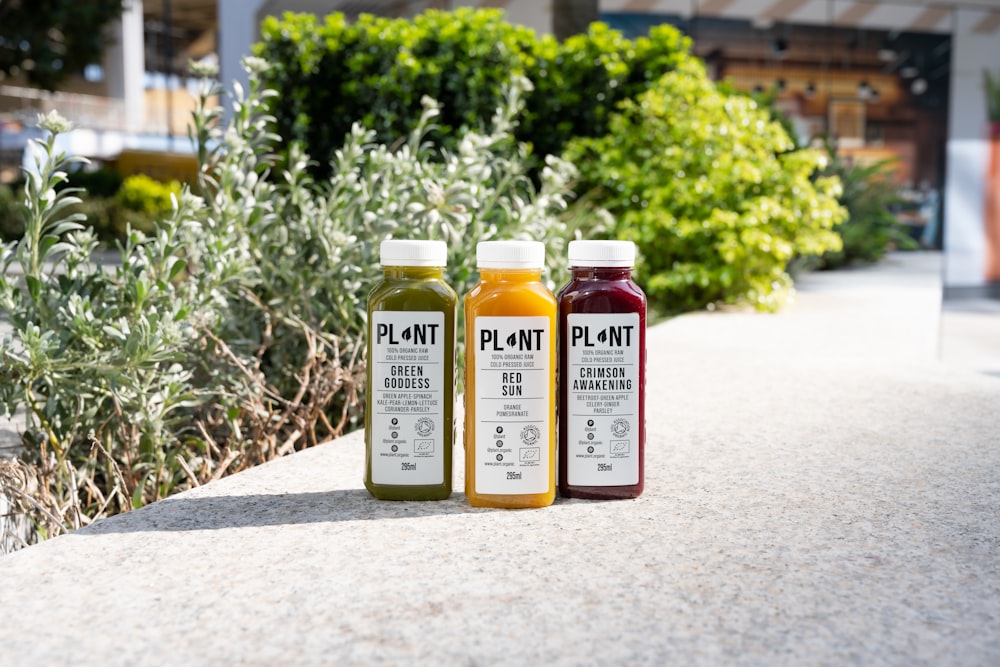 three bottles of juice sitting on a sidewalk