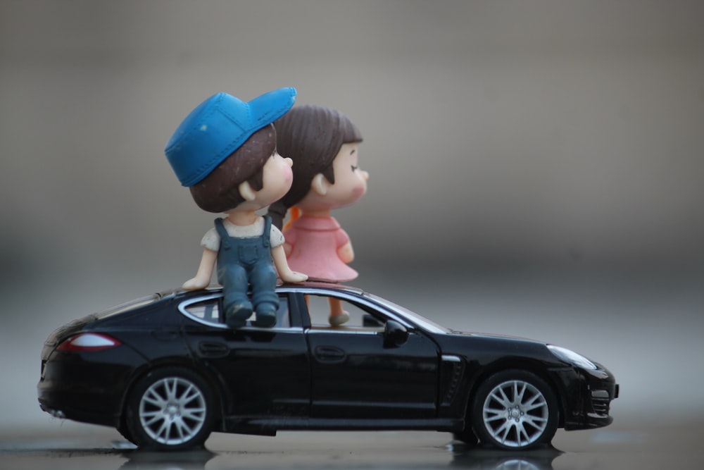 a couple of figurines sitting on top of a car
