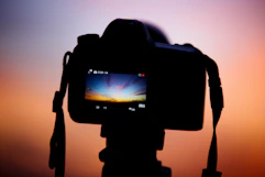 a camera with a blurry background of a sunset