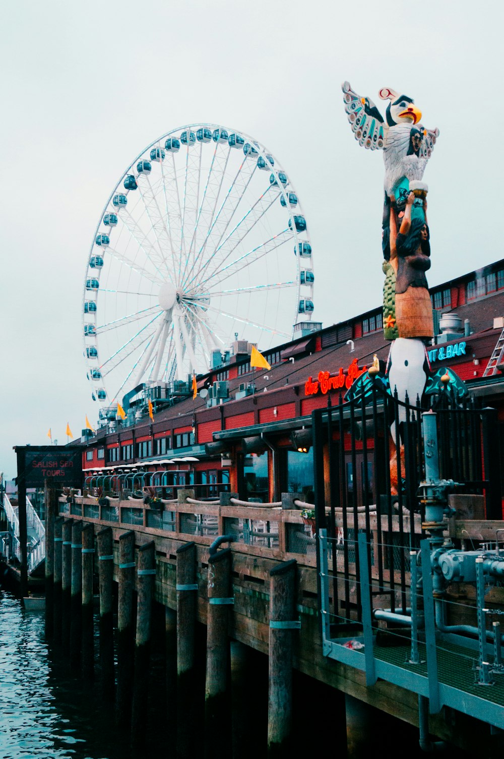 a statue of a man on a pier next to a ferris wheel