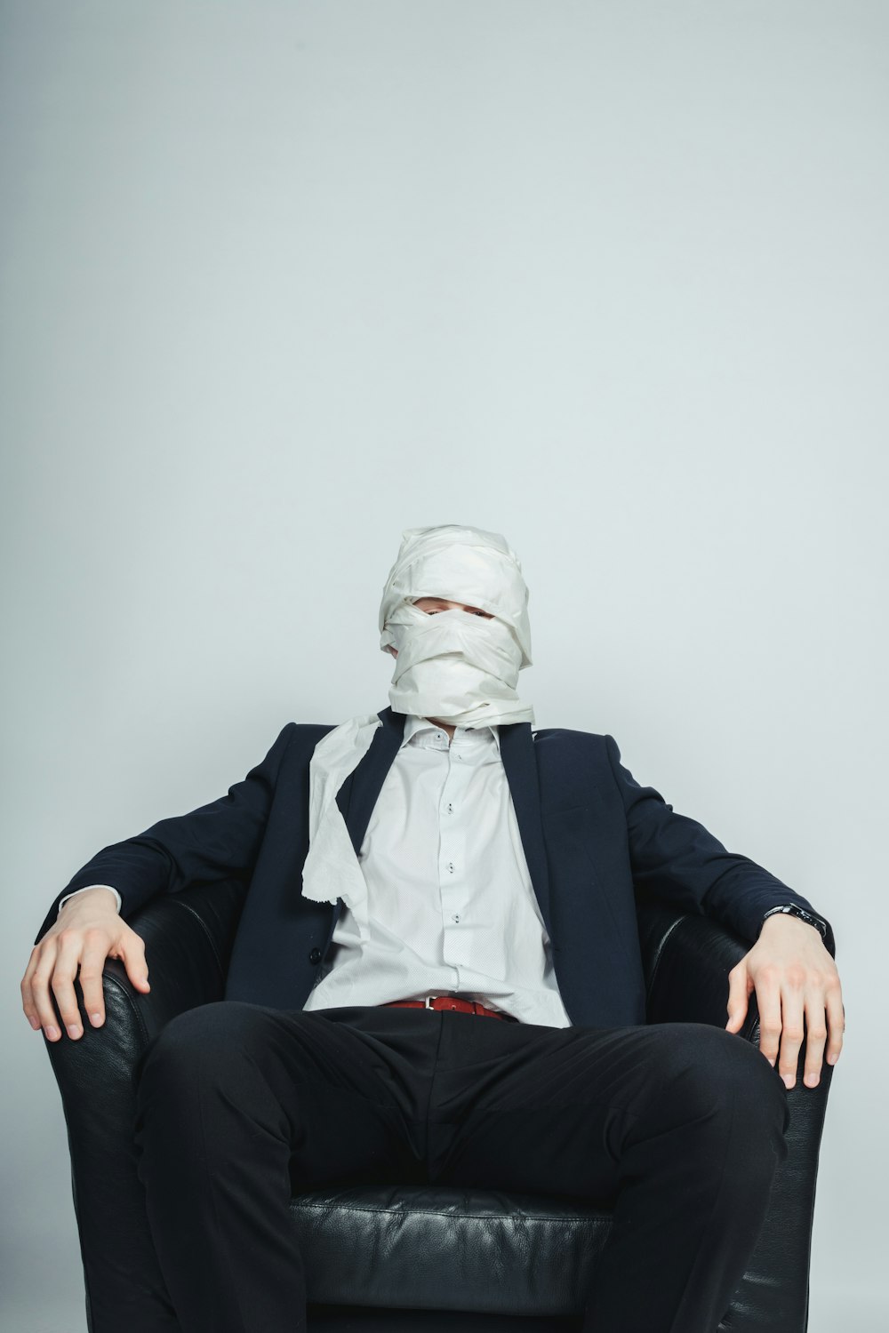 um homem sentado em uma cadeira com uma máscara no rosto