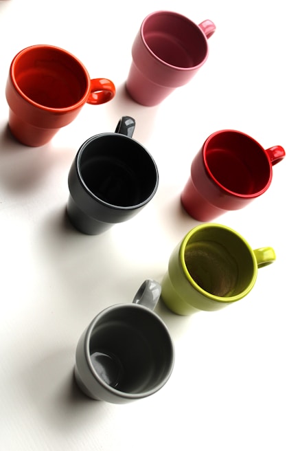 A set of insulated mugs in various colors arranged neatly on a kitchen counter