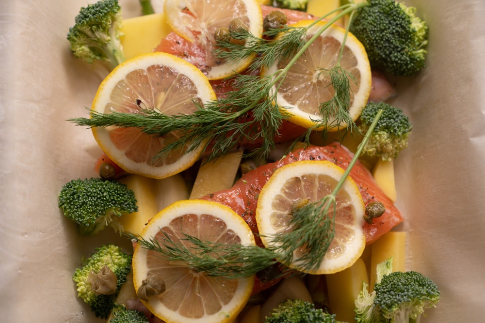 a white bowl filled with sliced up lemons and broccoli