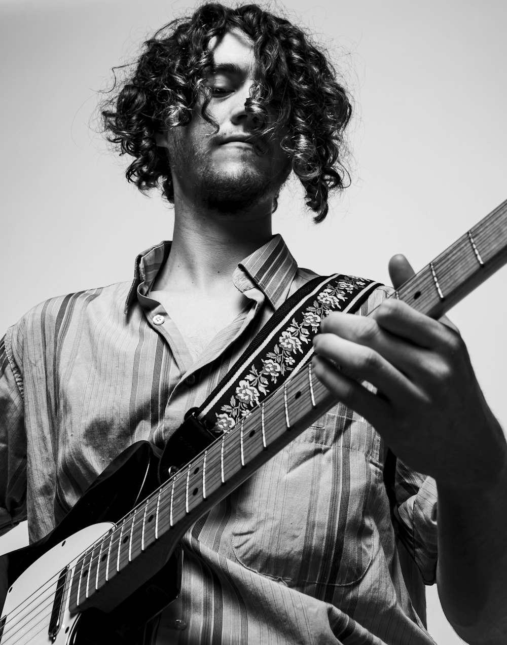 a man with curly hair playing a guitar