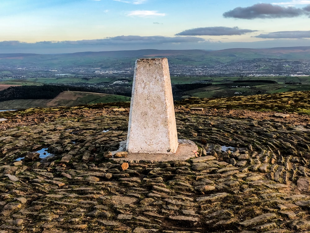 a stone obelisk on top of a grassy hill