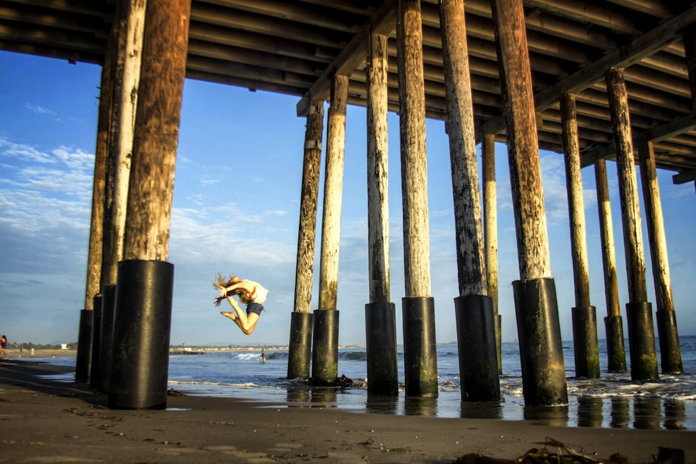 a person jumping into the water under a pier