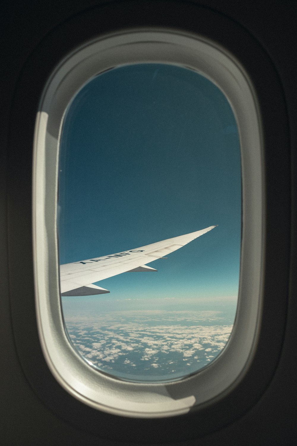 an airplane window with a view of the sky and clouds