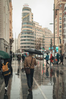 Gentle rain falling on a busy city street with umbrellas and wet pavements