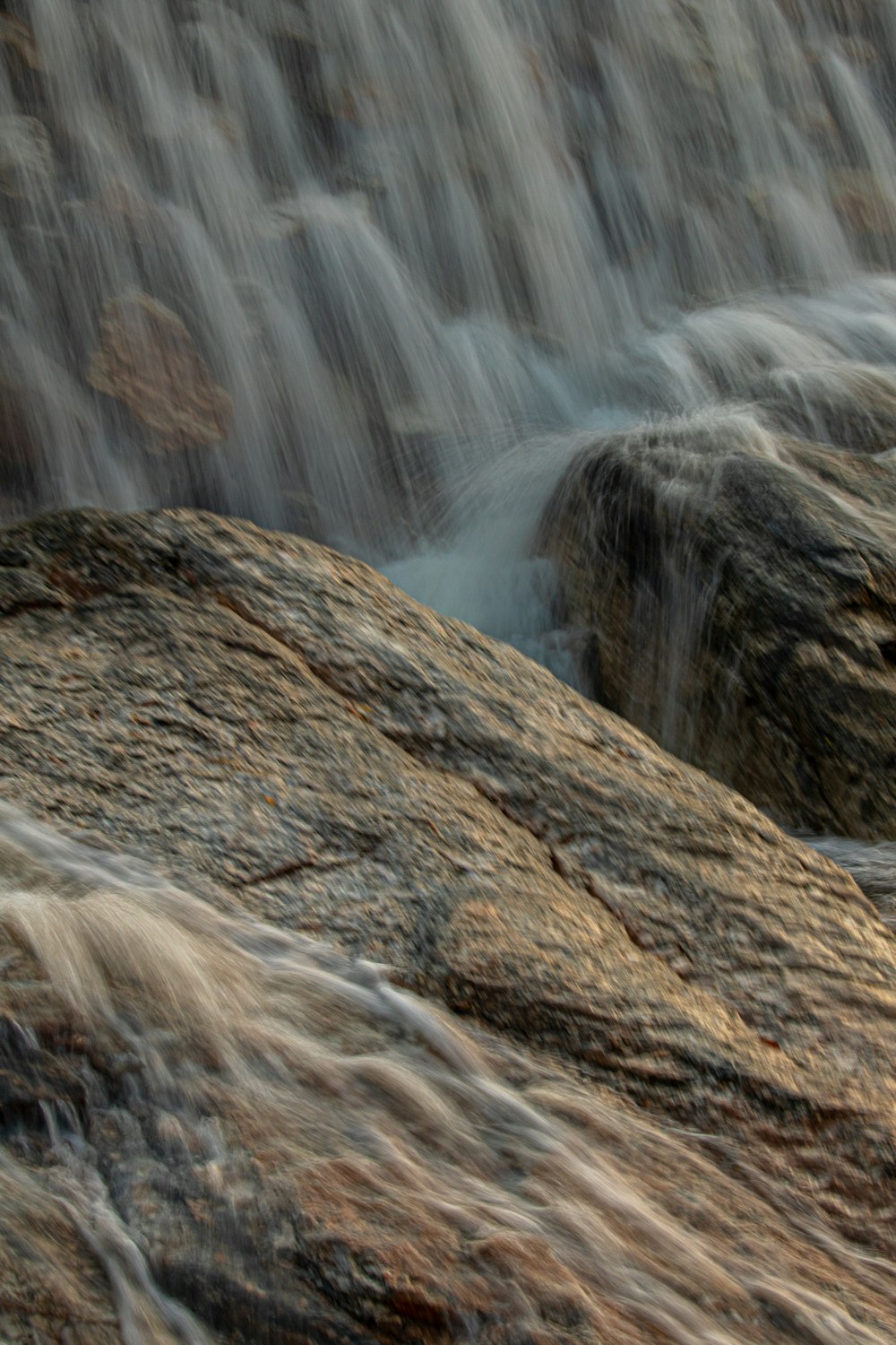 a close up of a waterfall with rocks in the foreground