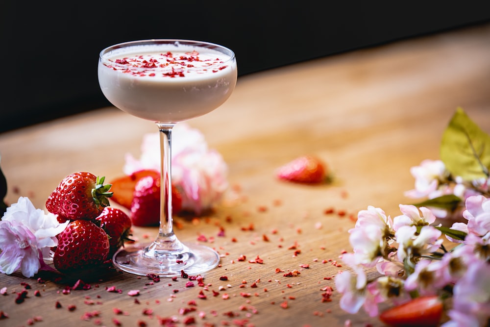 a close up of a wine glass on a table with strawberries