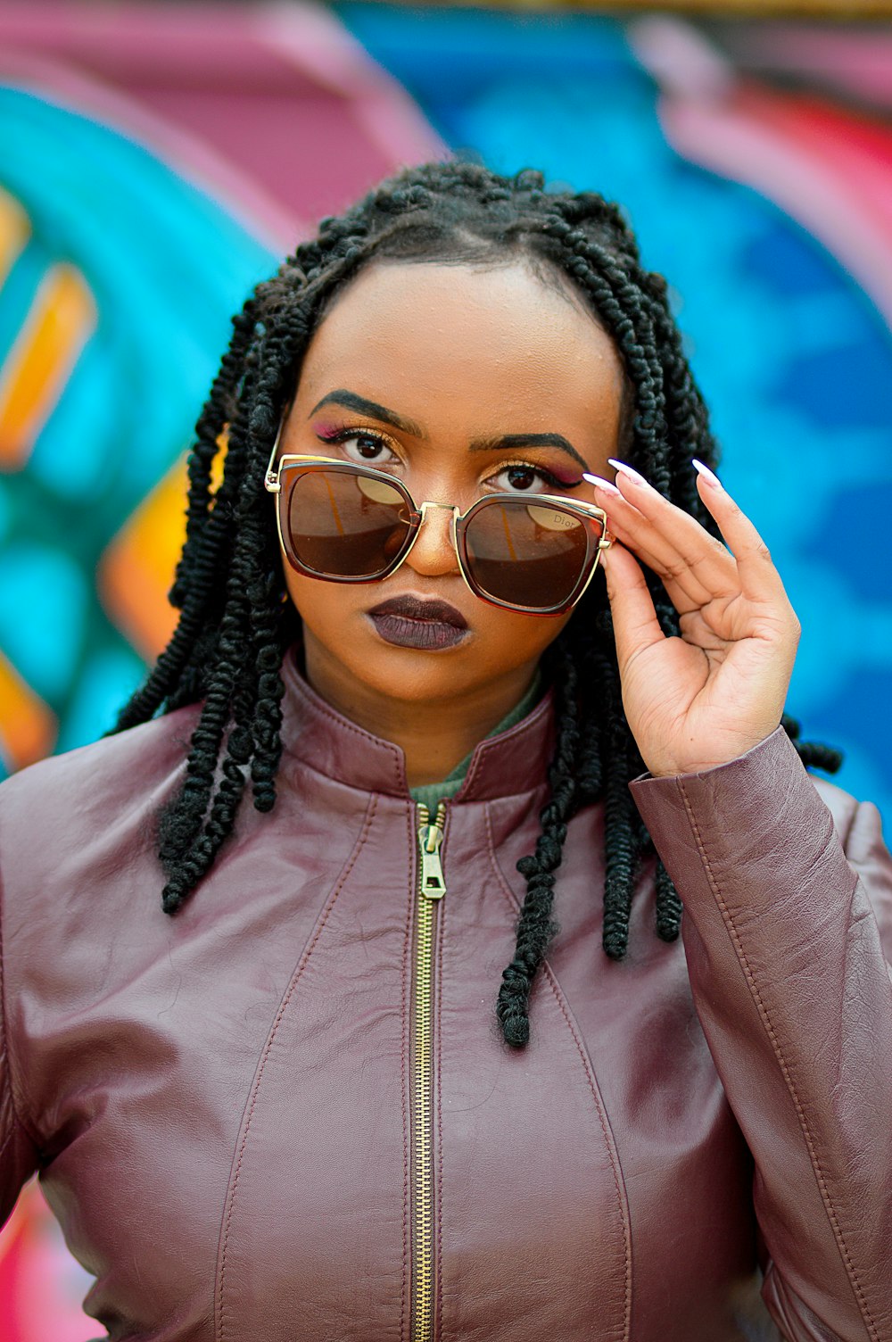 a woman in a brown leather jacket and sunglasses