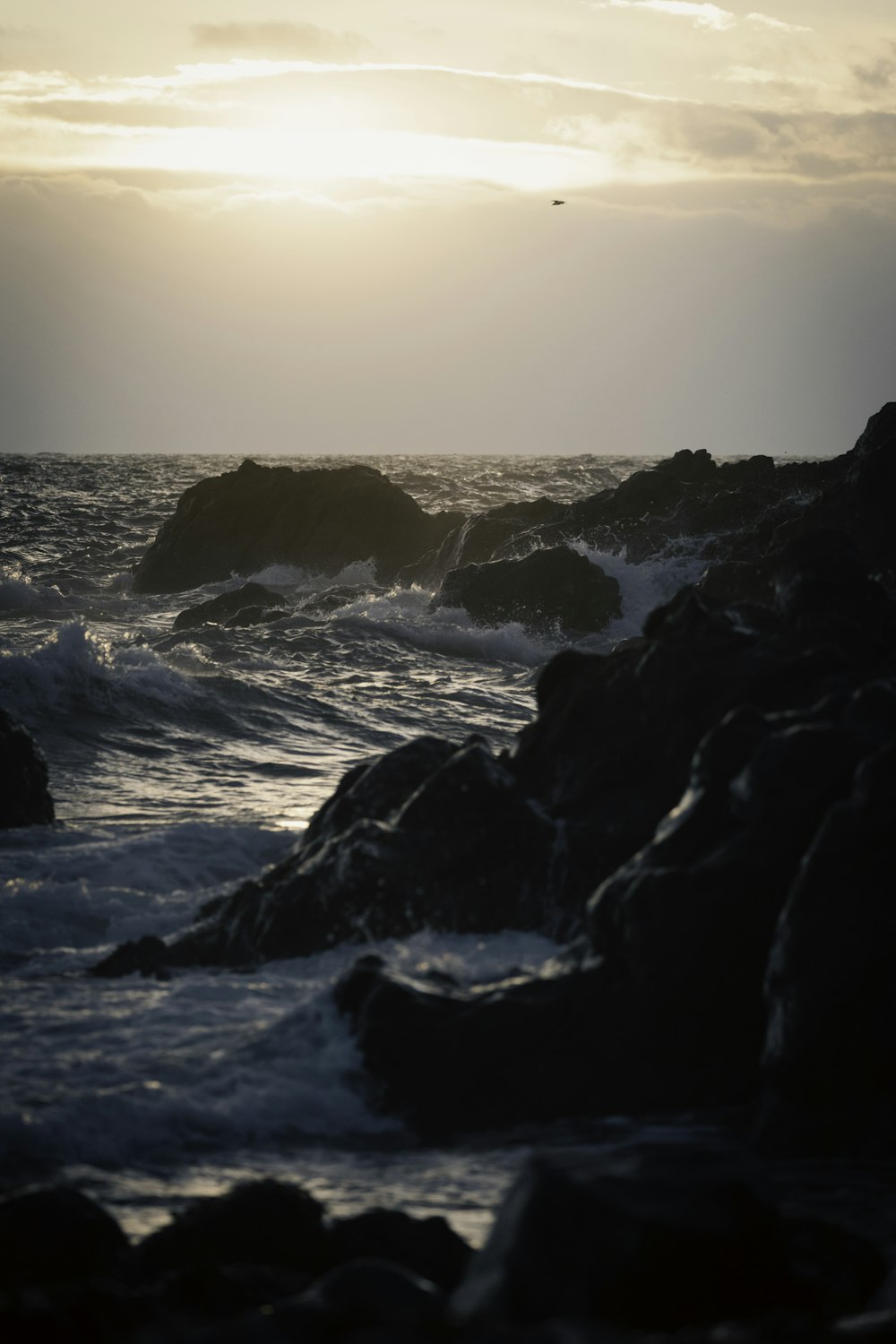 the sun is setting over the ocean and rocks