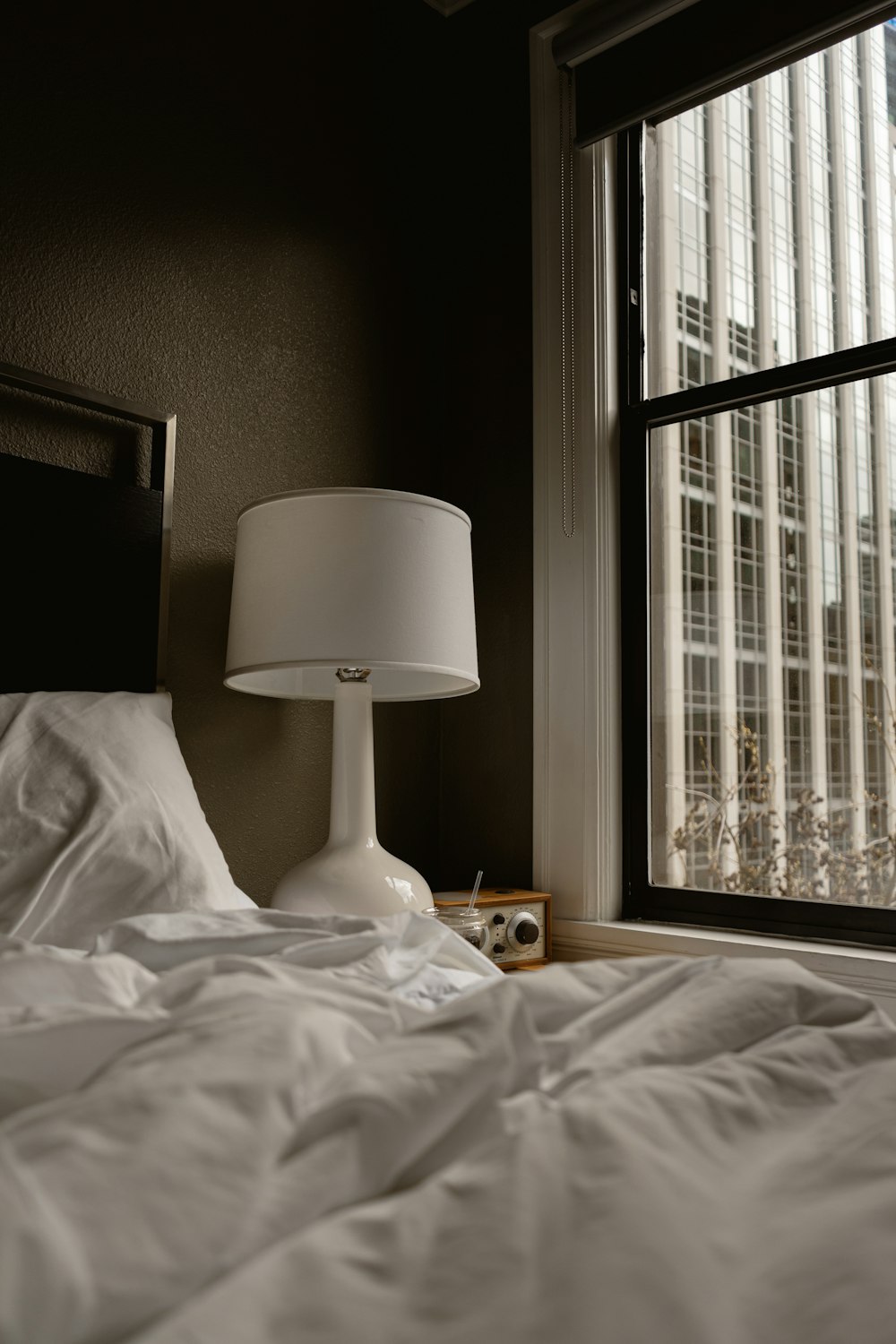 a bed with a white comforter and a white lamp