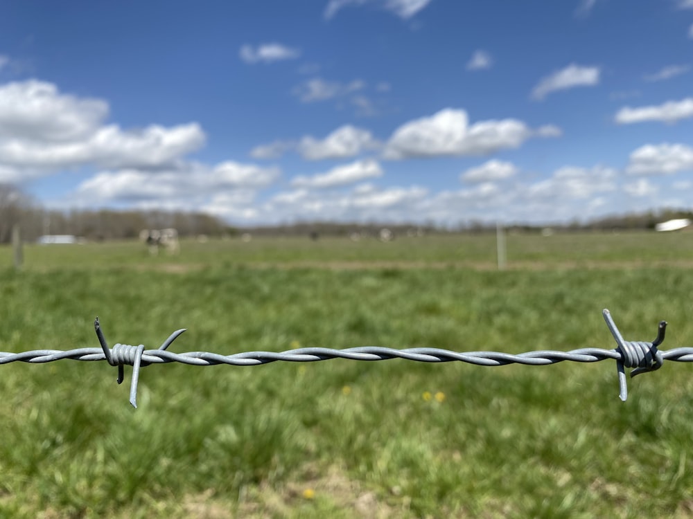 a barbed wire fence with a field in the background